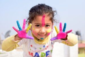 Criança com as mãos e o rosto pintado